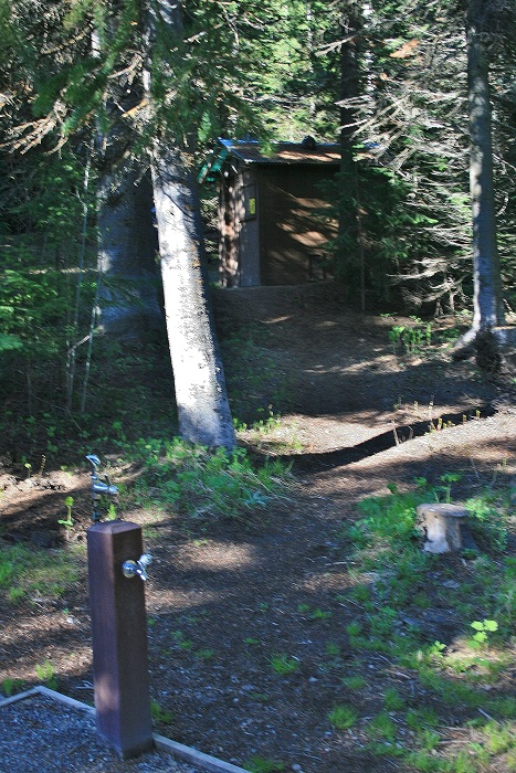 Pettit Campground drinking water with outhouse in background.